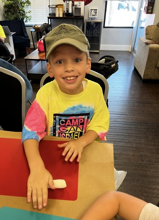 Camper smiling at camp in a colorful camp shirt